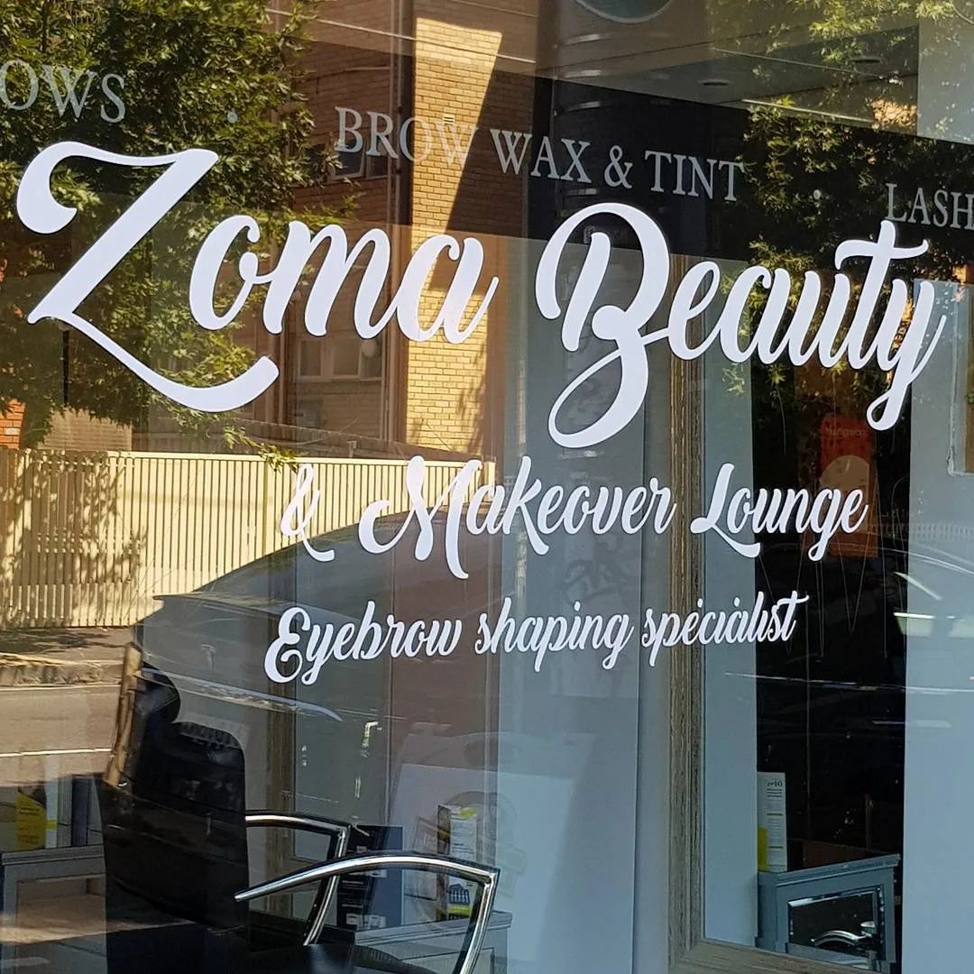 Zoma Beauty shopfront glass with the script decal — Eyebrow shaping specialist