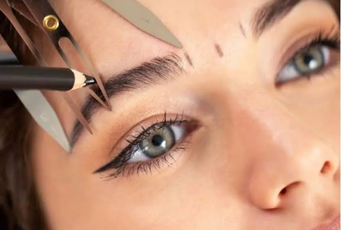Brow being mapped with a stencil and marker mid-treatment