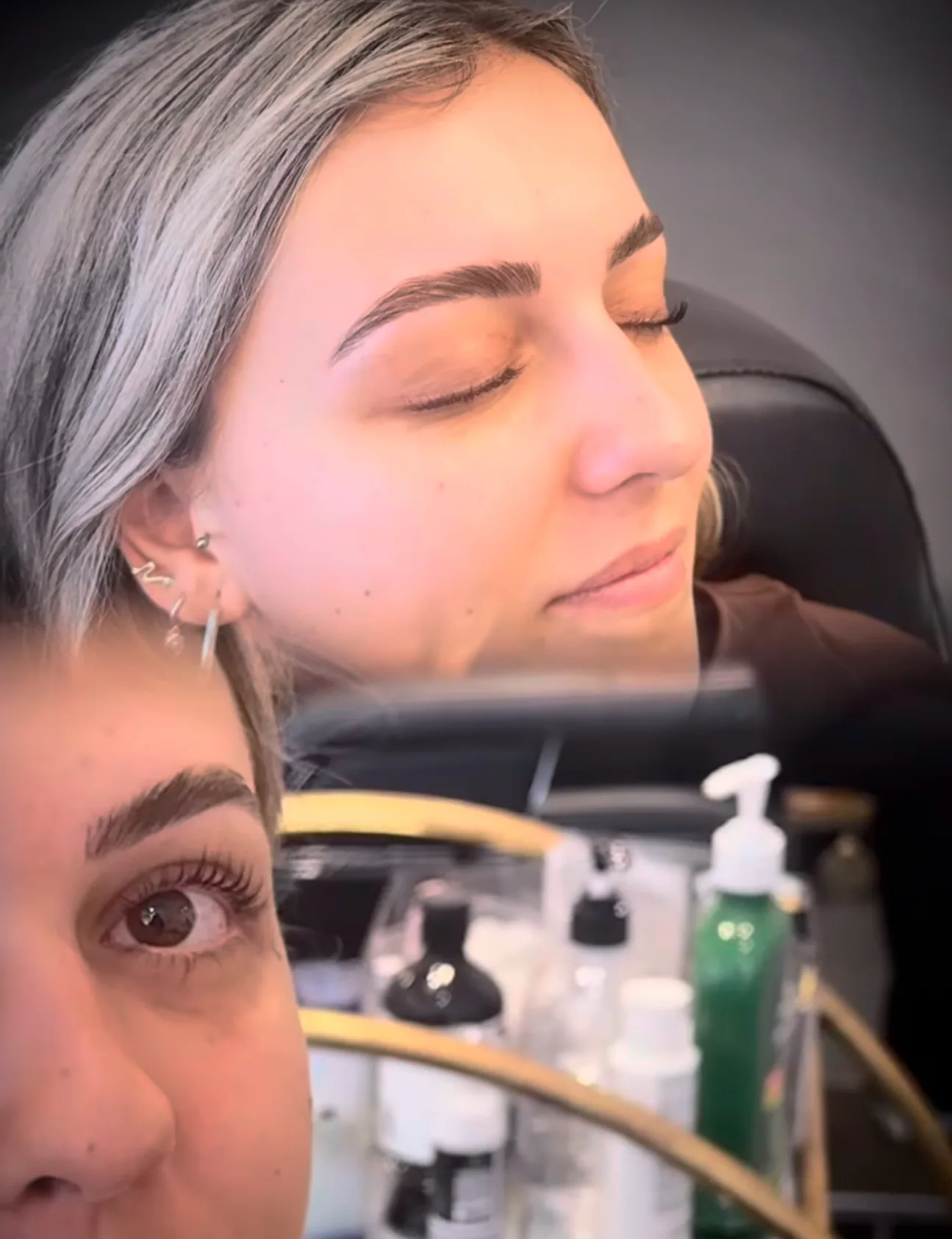 Reclined client having a brow treatment, operator's eye in foreground