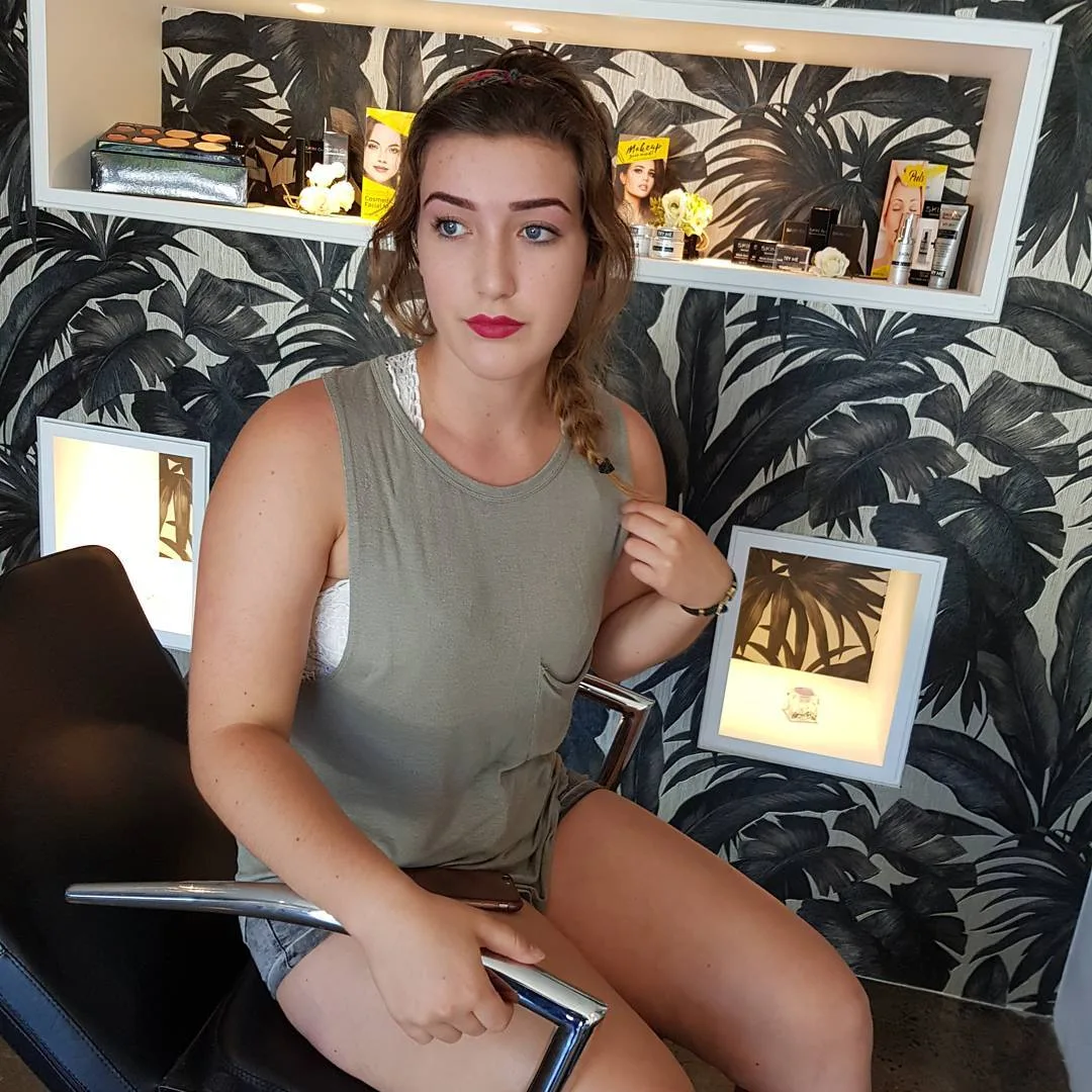 Client in the salon against the black palm-leaf feature wall