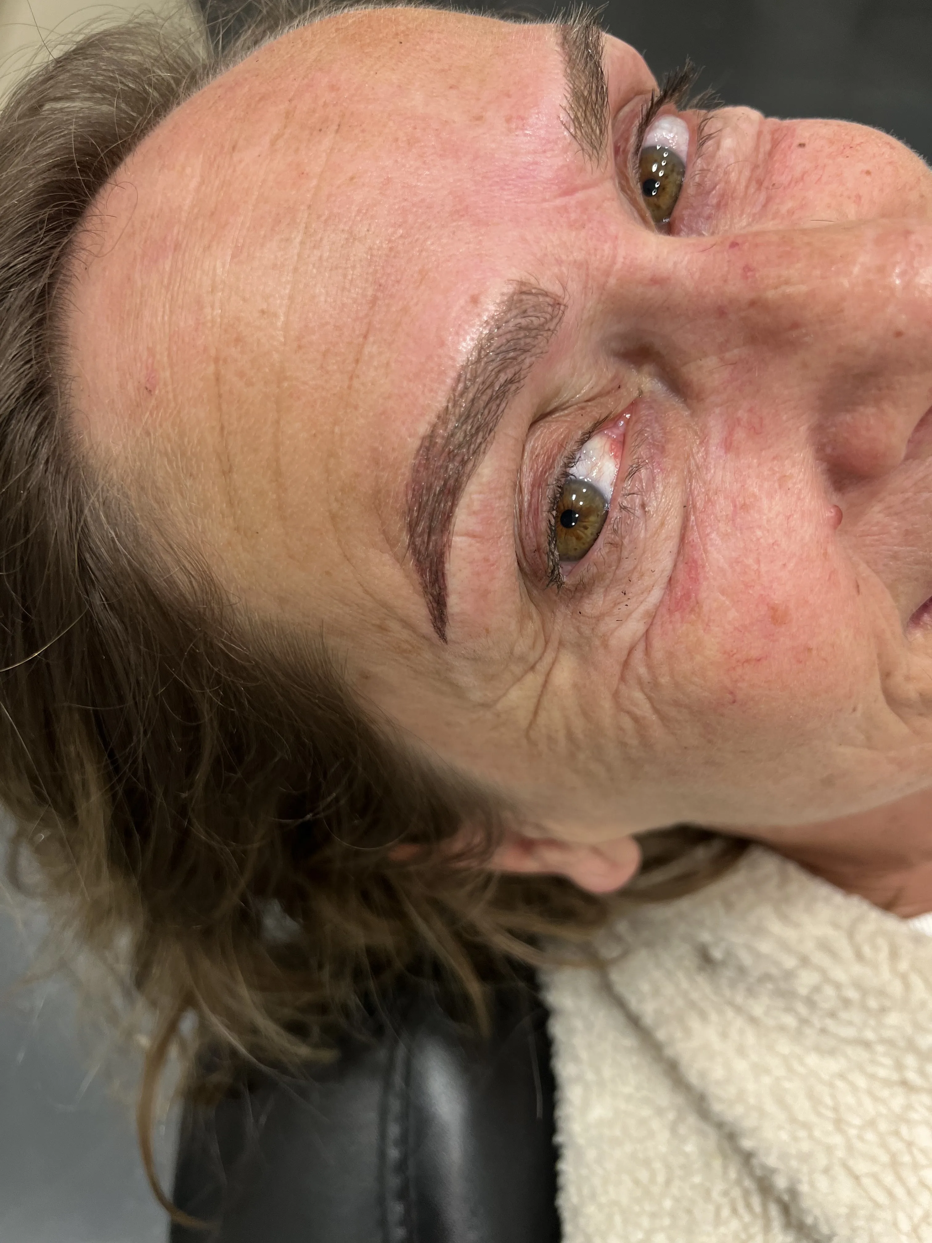 Mature client reclined after brow work — brow shaping result by Zoma Beauty